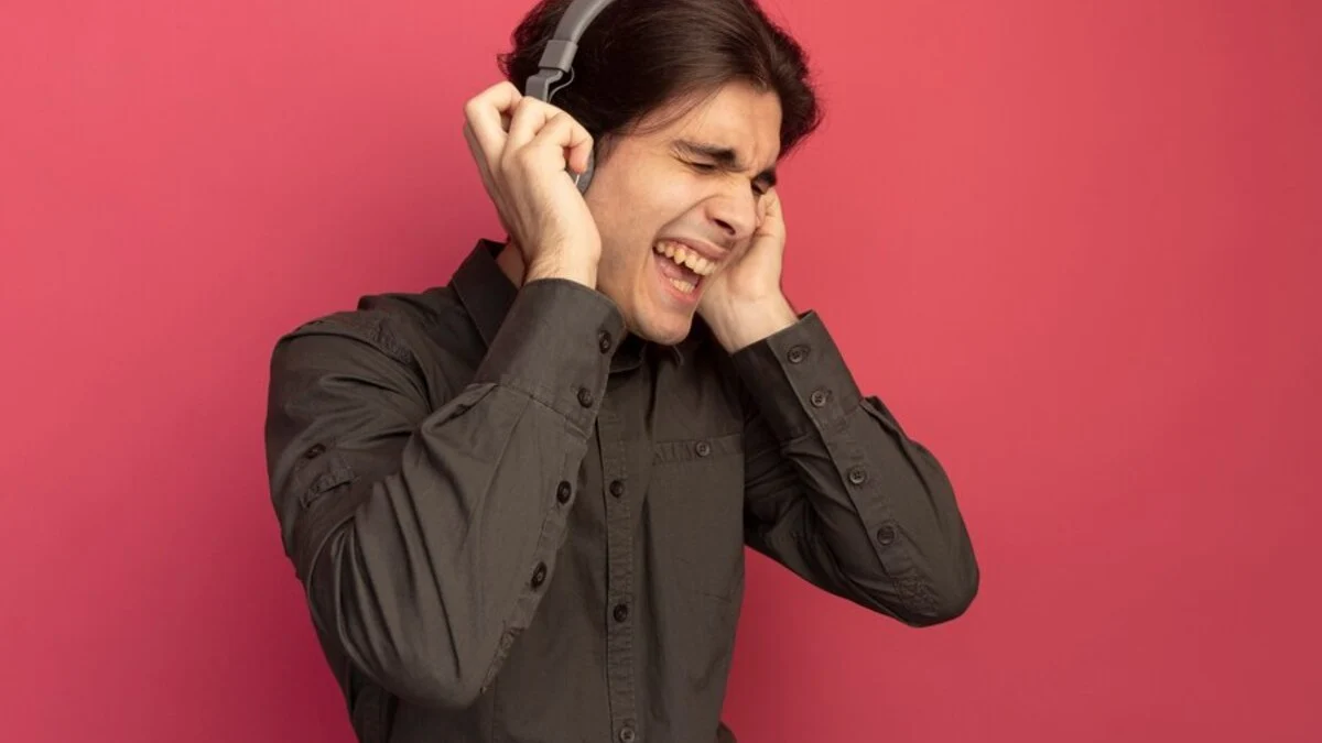 Hearing Loss | joyful-with-closed-eyes-young-handsome-guy-wearing-black-t-shirt-with-headphones-listen-music-isolated-pink-wall