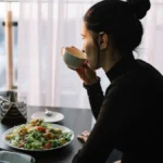 Monsoon Diet | young-woman-drinking-from-cup-table-with-salad-near-window