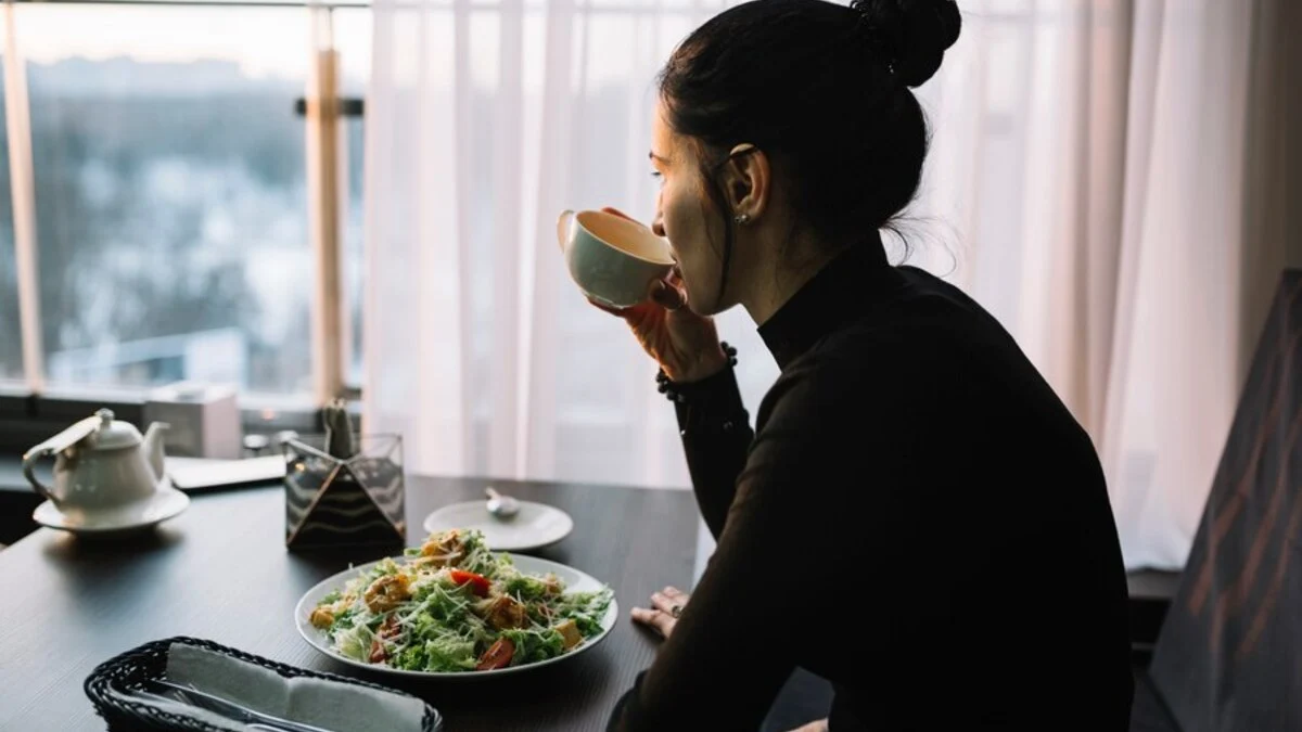 Monsoon Diet | young-woman-drinking-from-cup-table-with-salad-near-window